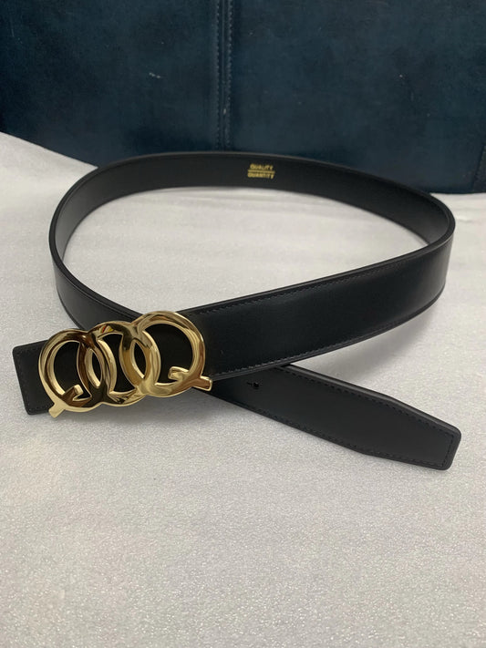 Black belt with gold buckle on a light gray surface
